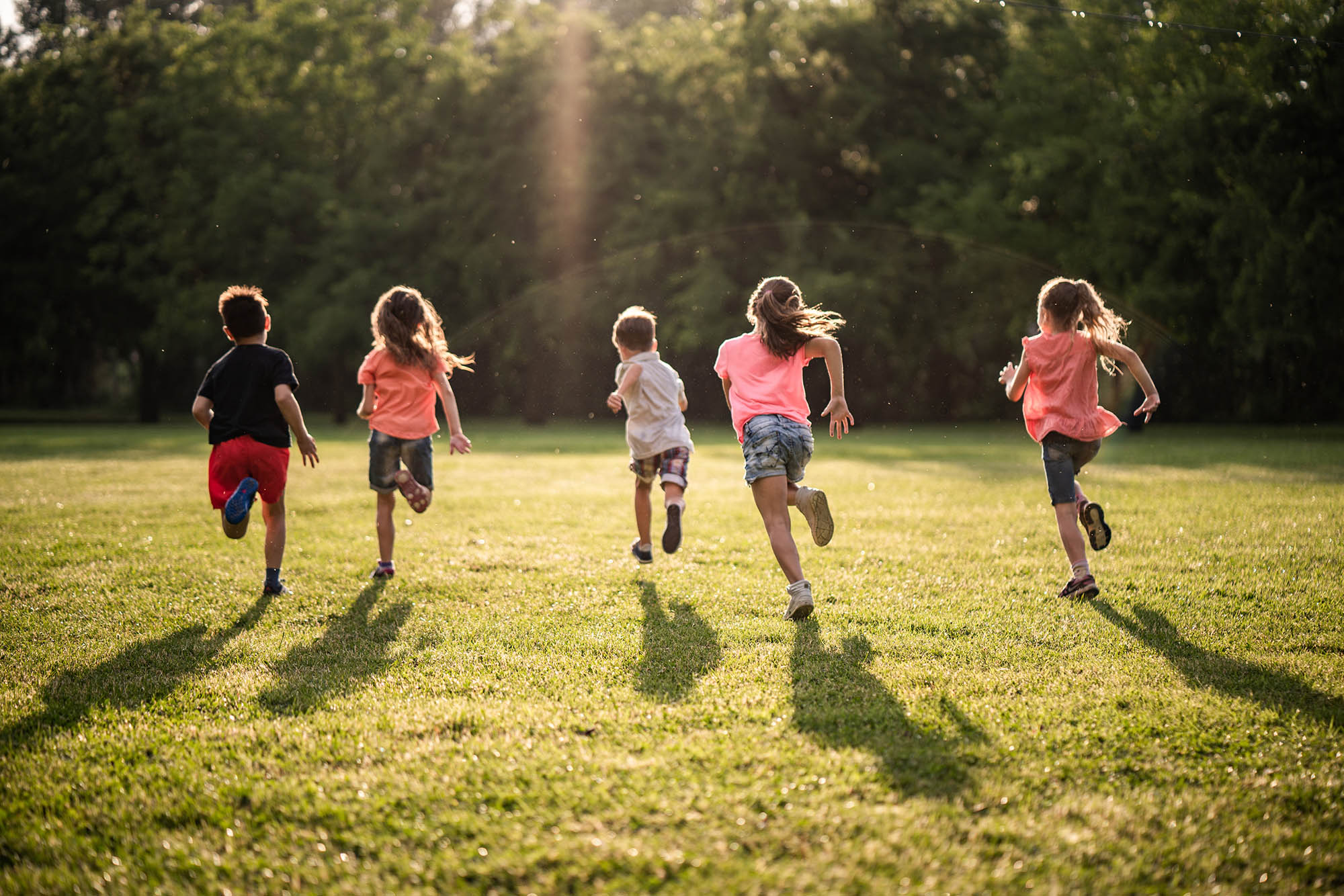 Back view group of children running in nature peak pediatrics